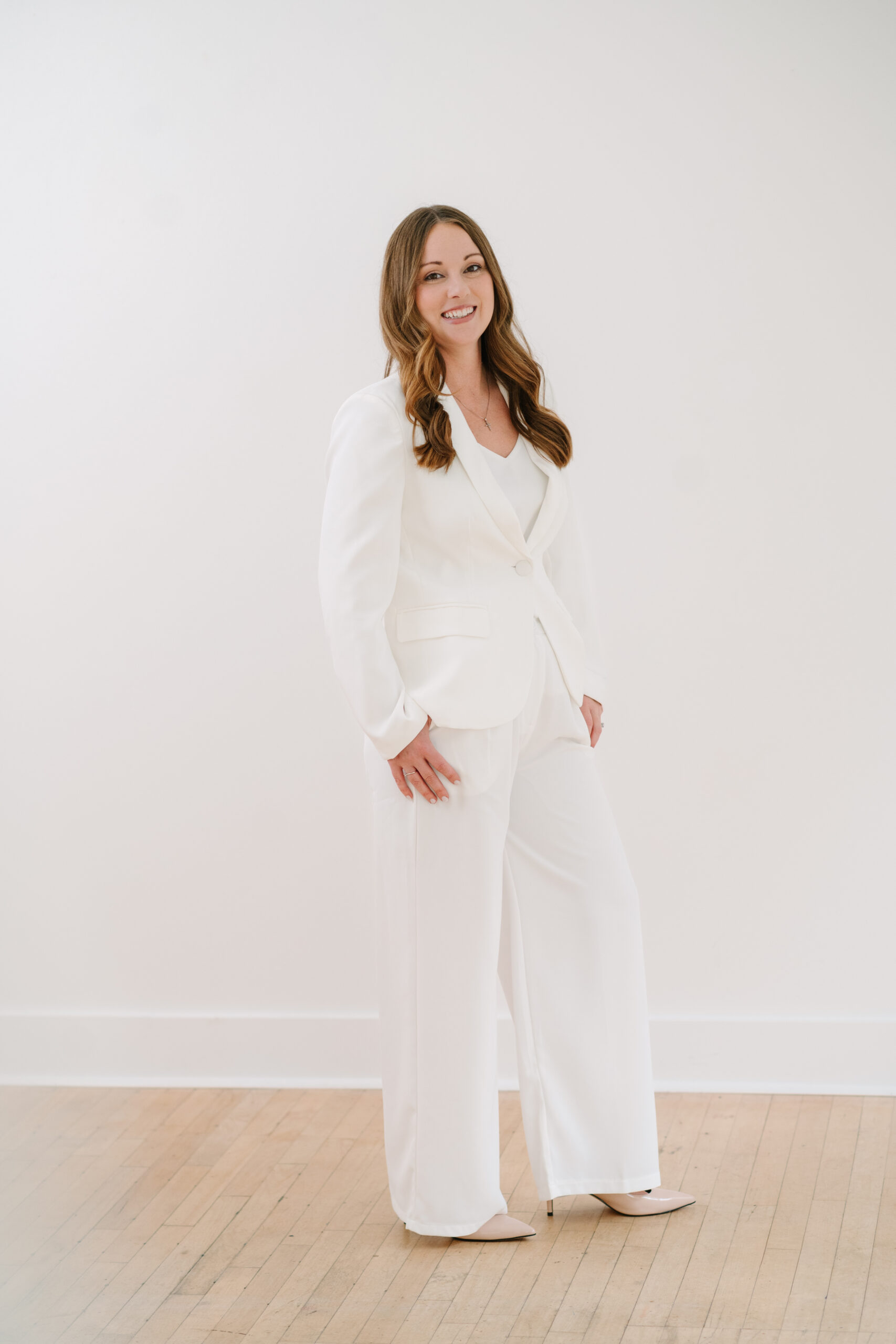 A lady in a white suit smiling at the camera full body length