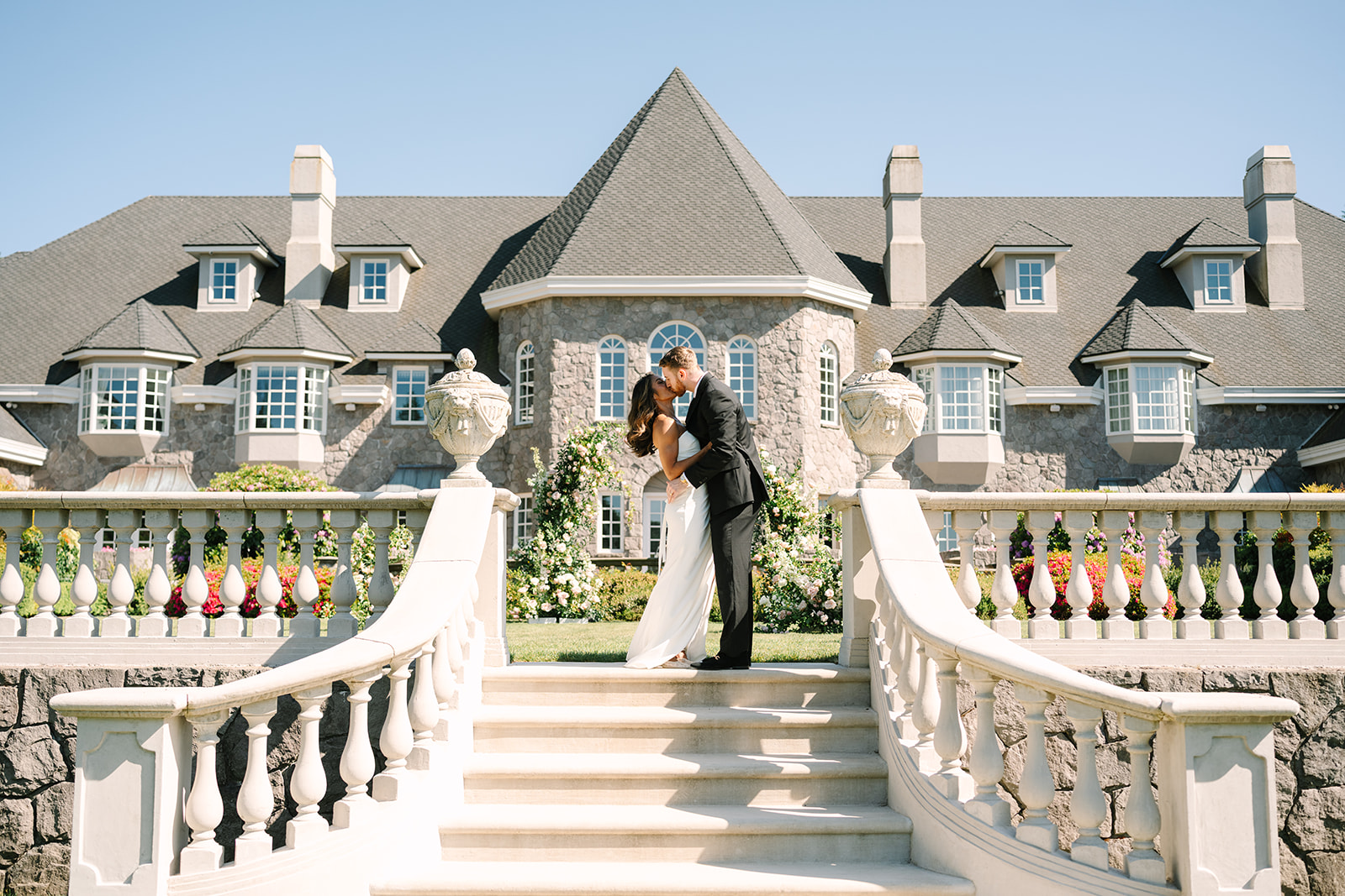 bride and groom kissing in front of their venue on the stairs