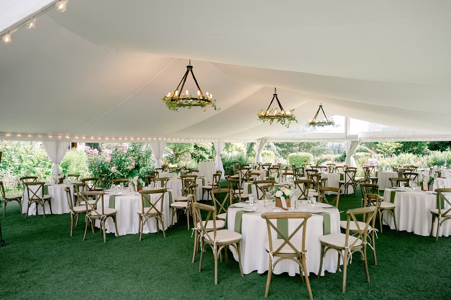 twinwillowgardens round tables with wood chairs under a canvas white wedding tent with chandeliers